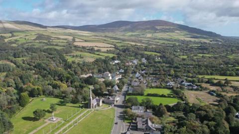 An arial view of St John's, you can see lots of trees around the roads, there is a hill in the background.