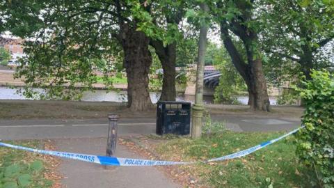 A police cordon in front of the New Walk area of York. You can see the River Ouse and Skeldergate bridge in the background of the picture