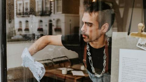 A cafe worker cleans a front window
