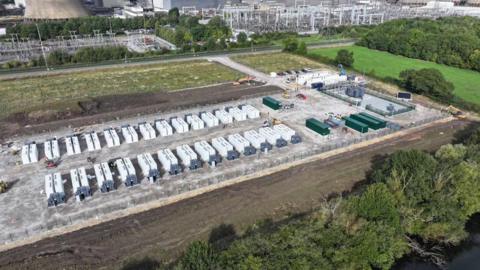 A large battery energy storage system located in a green field near to a power station.