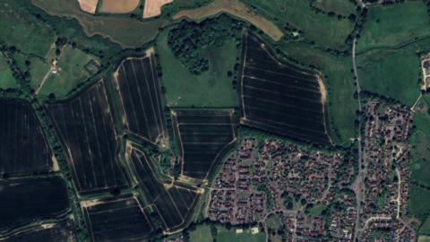 A satellite image of fields on the edge of a rural village in West Sussex.