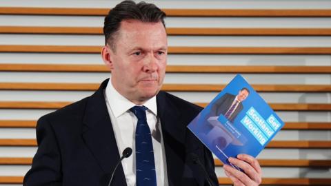 Russell Findlay holding the party's manifesto at the launch.