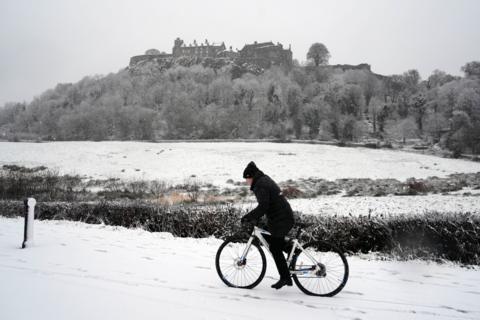 A person rides their bike through the snow