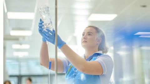 Nurse inspecting drip.