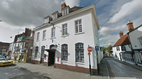 The front of the Post Office branch in Horncastle Market Place. A white building with a black door and has three attic windows with white window frames.