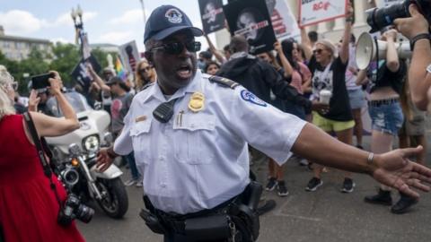 A US Capitol Police officer creates a police line as anti-abortion activist and abortion rights activists protest outside the Supreme Court in Washington, DC, USA, 24 June 2022.