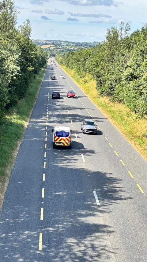 A still of the N2 road in Carrickmacross in County Monaghan. It is a single-file road with traffic flowing in each direction.