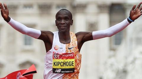 Eliud Kipchoge with his arms outstretched in celebration as he crosses the line to win the London Marathon