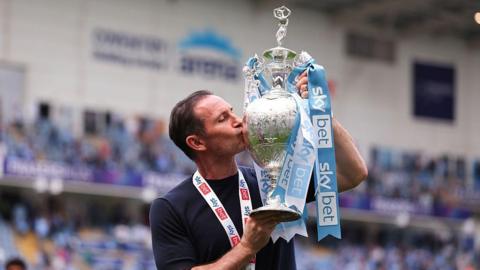 Frank Lampard in a dark blue t-shirt kisses the Championship trophy