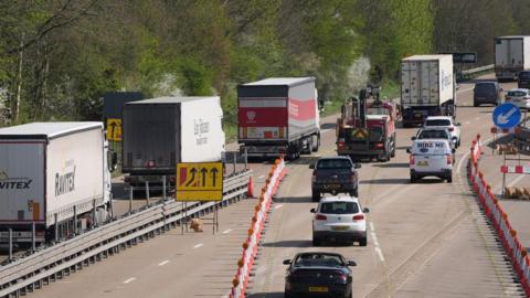 Queues of lorries and other vehicles travelling away from the camera on a motorway