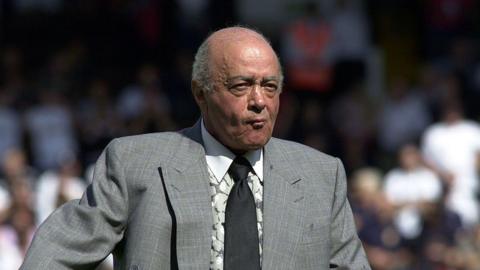 Al Fayed wearing a suit in the foreground against a crowd in the background