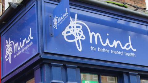 The outside of a blue Mind charity thrift shop with the Mind squiggle logo