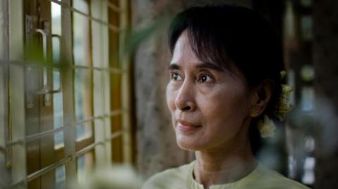 Aung San Suu Kyi looks out a window. 