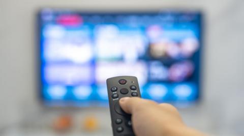 A remote being pointed at an out of focus TV screen