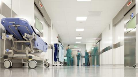 A trolley in a hospital corridor with medics working in the distance