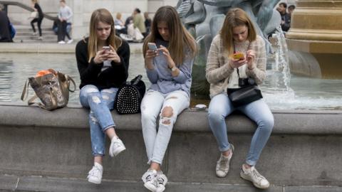 Teenage girls use smartphones
