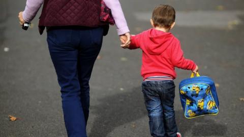 Woman holds child's hand