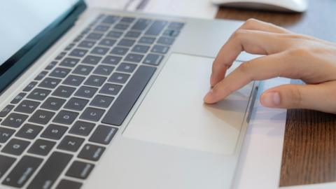 A hand touches the keypad of a laptop.