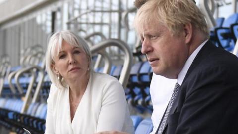 Nadine Dorries and Boris Johnson sitting in a stadium