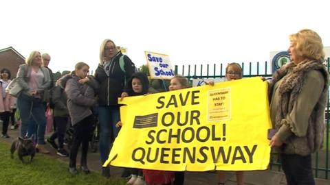 Campaigners outside school holding a save our school banner