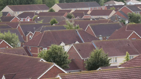 Several houses and their roofs can be seen in the image of a housing estate.