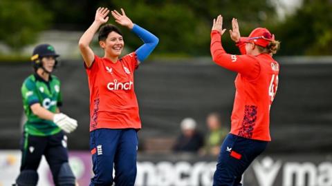 Issy Wong (left) and Hollie Armitage (right) celebrate a wicket for England against Ireland