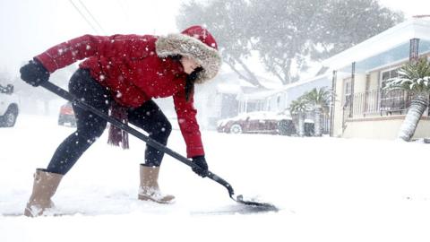 A woman shovels snow from her driveway in the Gentilly neighborhood during Winter Storm Enzo on January 21, 2025 in New Orleans, Louisiana.