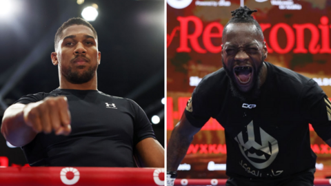 Anthony Joshua at the open workout poses with his fist out beside a picture of Deontay Wilder shouting i the ring