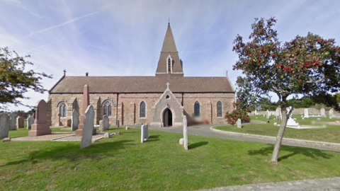 A picture taken from the front of the church in Jersey. There is grass and trees at the front of the image