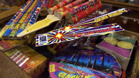 A pile of unopened fireworks with brightly coloured packaging.