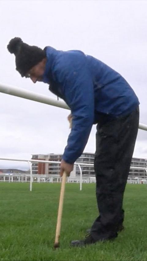 Racecourse groundsman pokes the ground. 