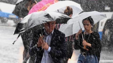 Pedestrians hold umbrellas during wet weather in Sydney, New South Wales