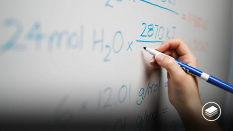 A photograph of a blue pen, writing a science equation on a whiteboard. 