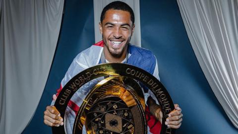 Chelsea defender Levi Colwill smiles as he poses with the Club World Cup trophy