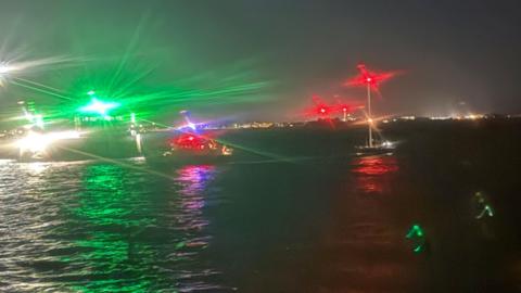 A blurry view of a yacht off the coast of Guernsey in the dark.