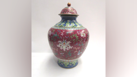 An ornate Chinese vase from the 18th century. It has a aubergine coloured background with foliage design.