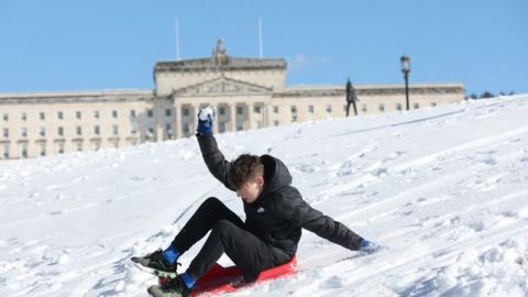 Boy sledding past Stormont