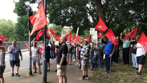 Unite members wave flags and placards on the picket line