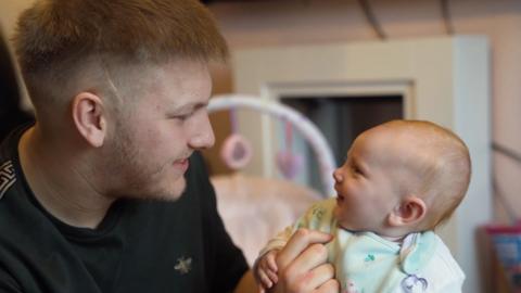 Man talking to baby, baby smiling.