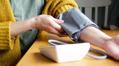 A person taking their blood pressure at home.