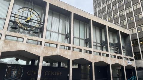 The civic centre in Southend-on-Sea. It is a grey building with large windows and a clock outside.