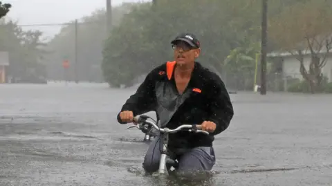 A resident  walking through floods in South Daytona, Florida