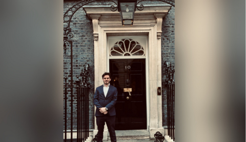 Paul Humpherson in a dark suit outside of 10 Downing Street. He is smiling.