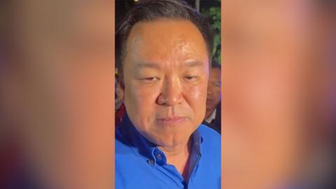 A man in a blue shirt looks at the camera