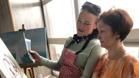 Maria paints with another woman