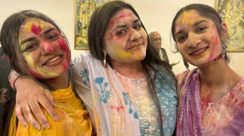 Three sisters dressed in Saris with colour on their face