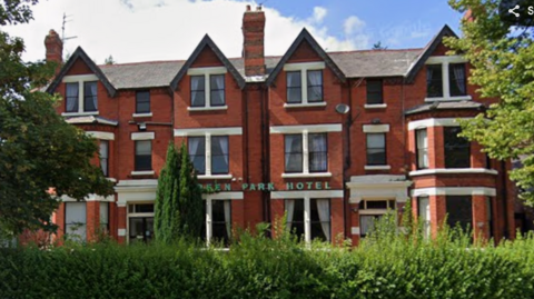 Image shows the Green Park Hotel in south Liverpool. It is a red-brick, three-storey early Edwardian building with trees in front of it and the words Green Park Hotel across the front. 