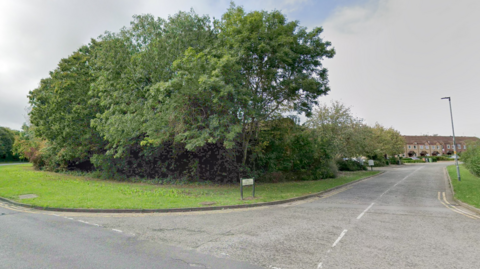 Junction showing a bend in the road with housing in the background