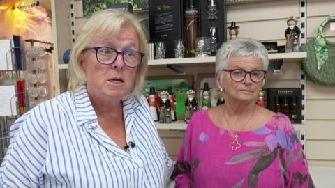 Mae Cynthia Davies a Karen Locke yn gweithio mewn siop yn y dre ac wedi gweld y gostyngiad 