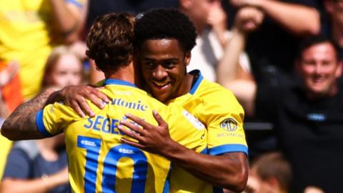 Adrian Segecic gets a hug from Ryan Kuvuma-McQueen after scoring Portsmouth's second at Lincoln
